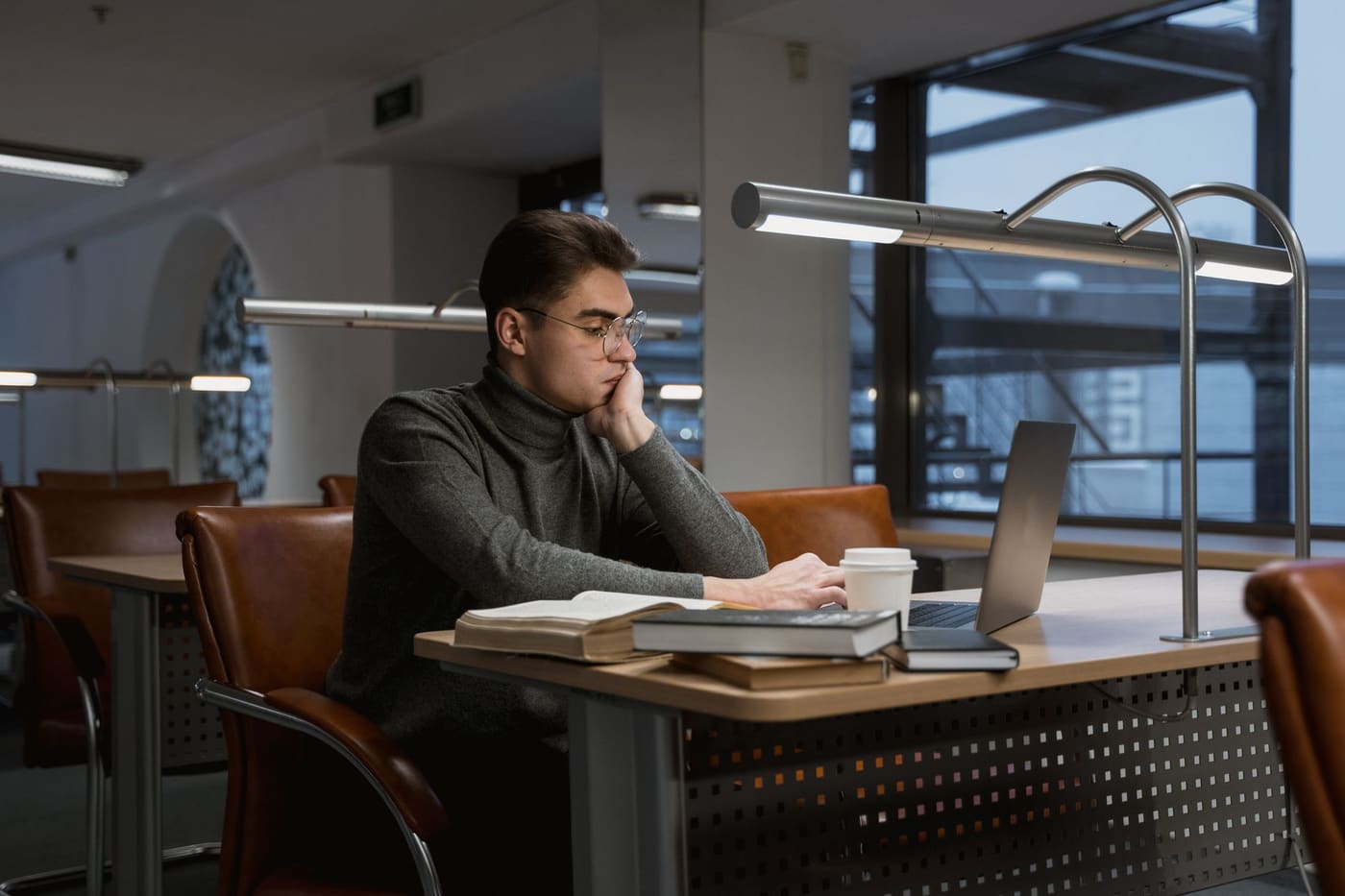 A person concentrating on a laptop in a quiet library