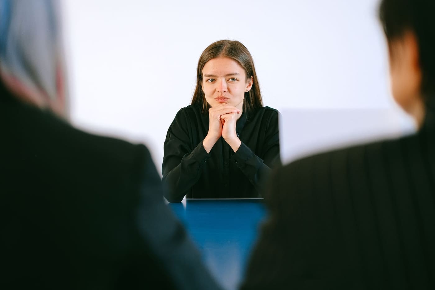 A woman sitting across a table from two interviewers in an office