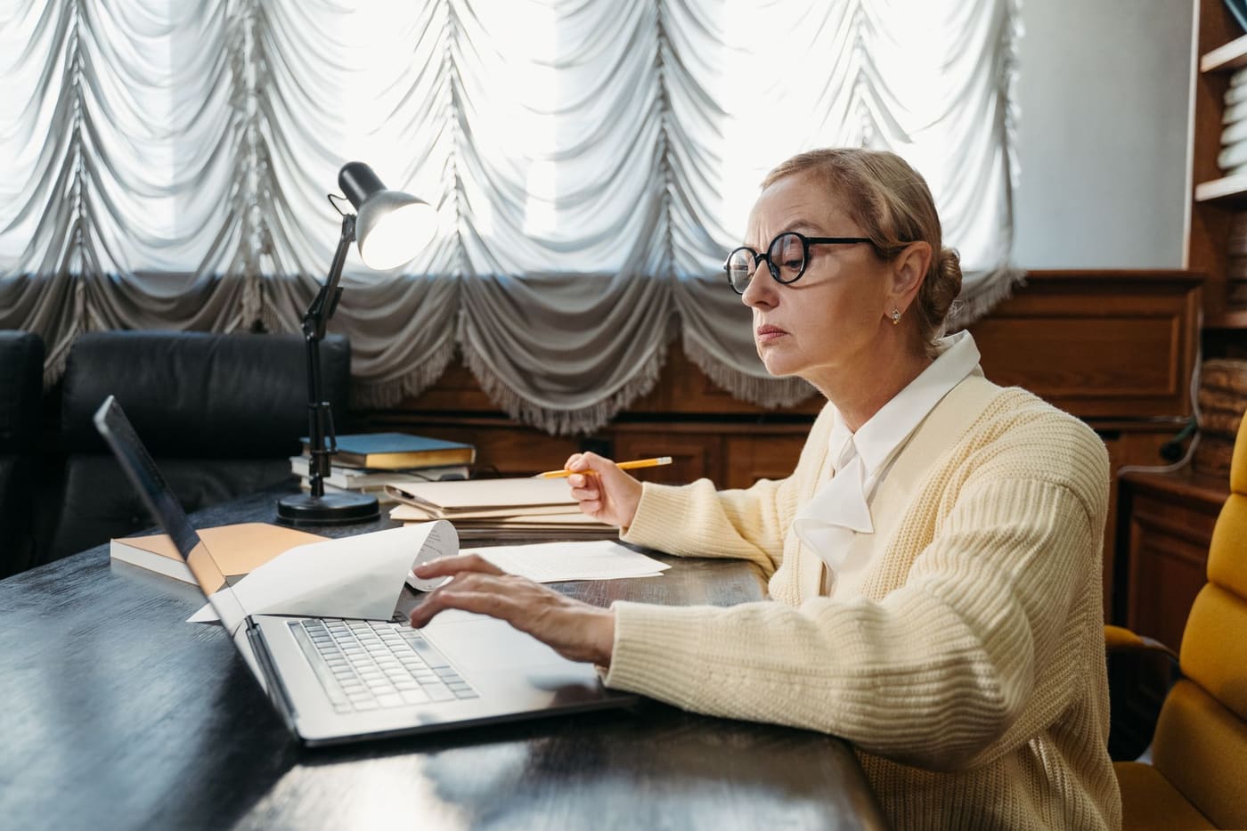 A middle-aged woman working on a laptop in a quiet library