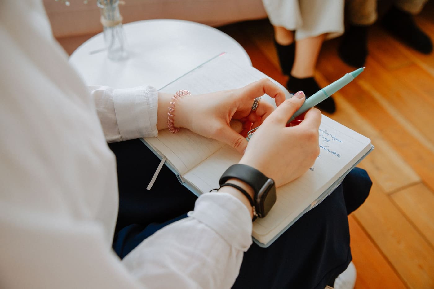 Hands writing in a notebook during a conversation